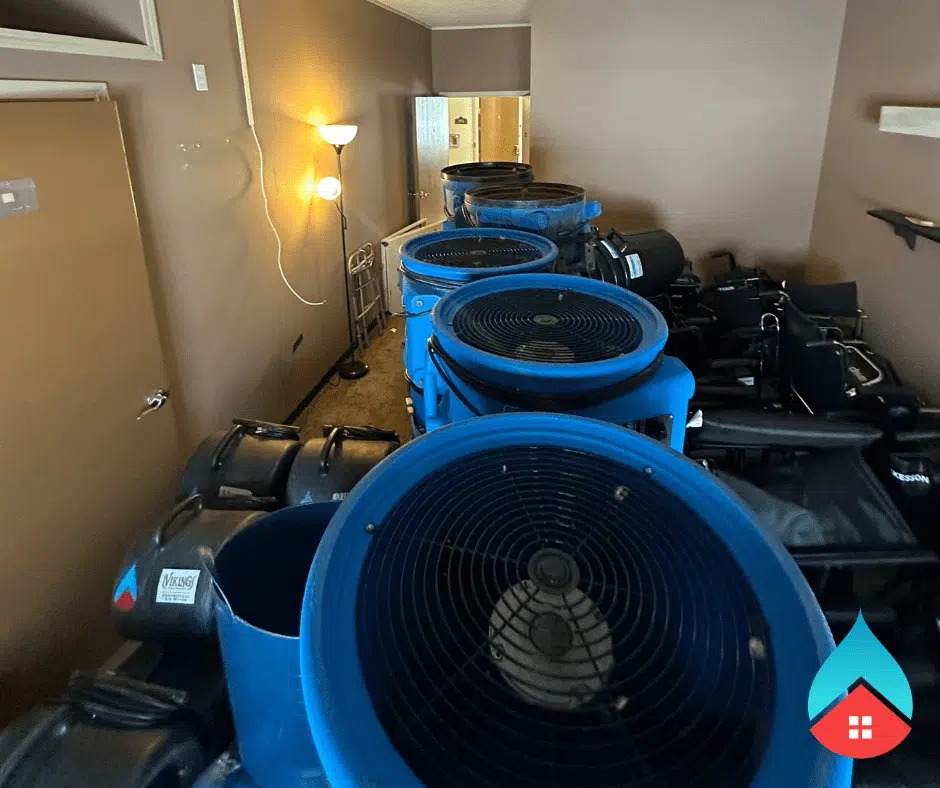 Water damage cleanup setup with multiple blue air movers drying wet surfaces